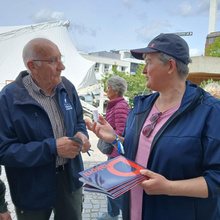 Merete Nørgaard taler med en mand på gaden og står med bladet Diakoni